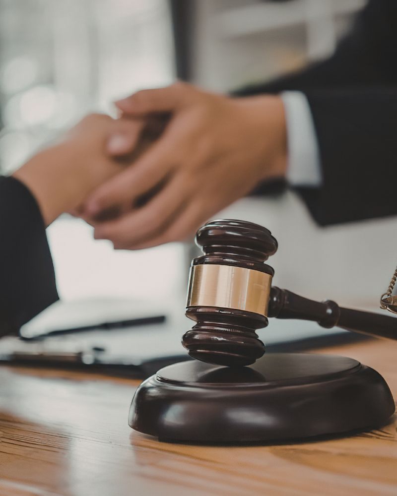 Lawyer shaking hands with client over legal documents and gavel representing criminal defense in Washington, DC